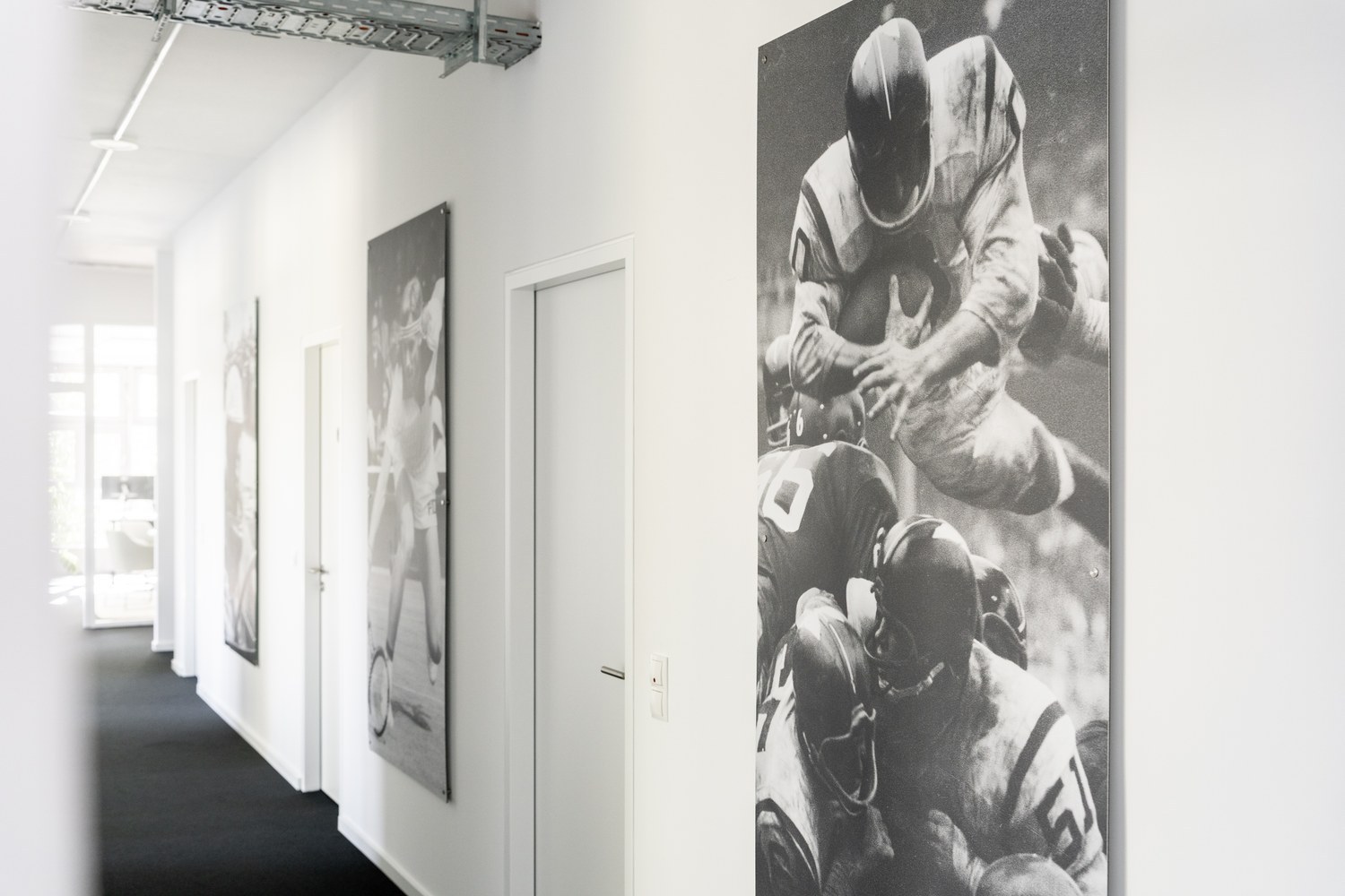 Flur mit historischen Sportfotografien an der Wand.