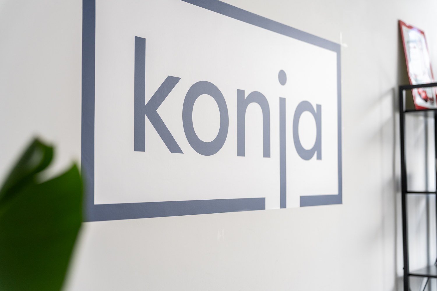 Fotografiertes konja-Logo an einer weißen Wand.
